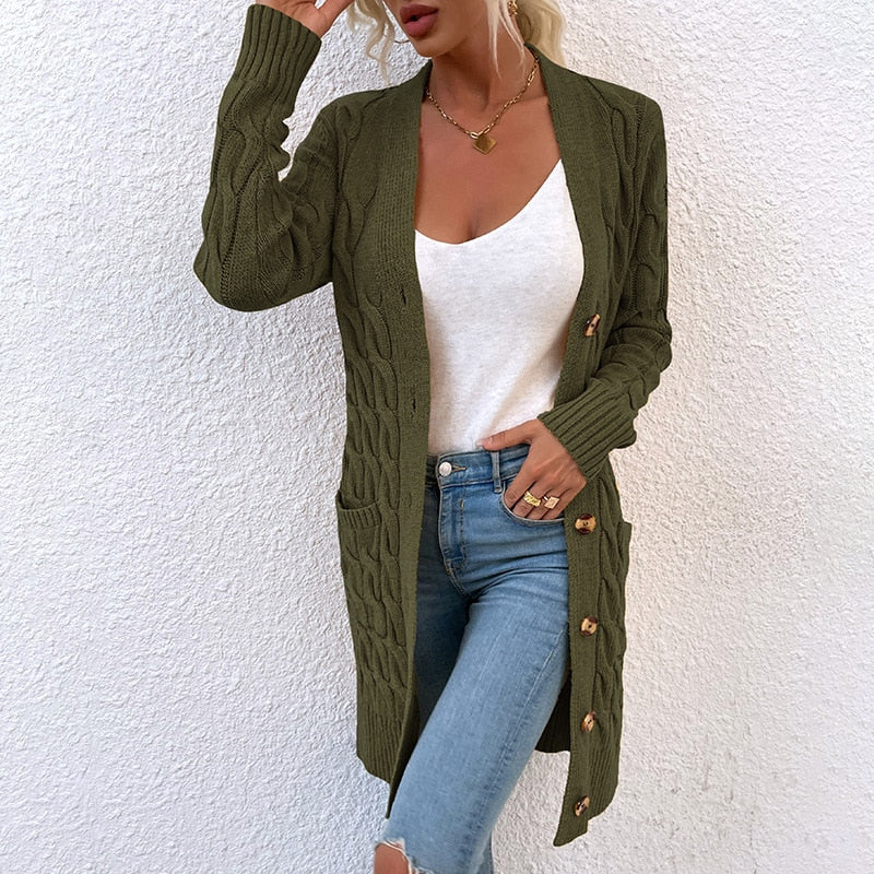 Frau in grünem Strickmantel mit Zopfmuster, weiße Bluse, blaue Jeans, modisch, lässig.