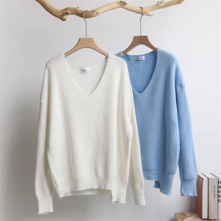 Zwei Strickpullover, cremeweiß und hellblau, V-Ausschnitt, Baumwolle, auf Holzkleiderbügeln.