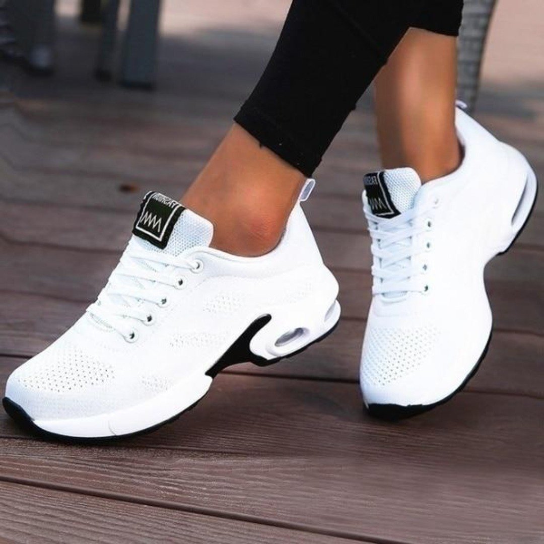 Weiße Damen-Sneaker, atmungsaktiv, sportlich, mit Luftpolstersohle, auf Holzterrasse.