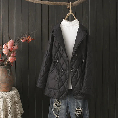 Schwarze gesteppte Damenjacke, elegant, Herbstmode, vor Holzwand drapiert.