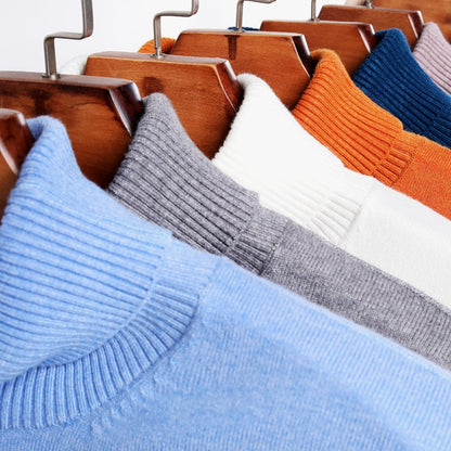 Bunte Strickpullover aus Wolle auf Holzkleiderbügeln, modische Herbst-Winter-Kleidung.