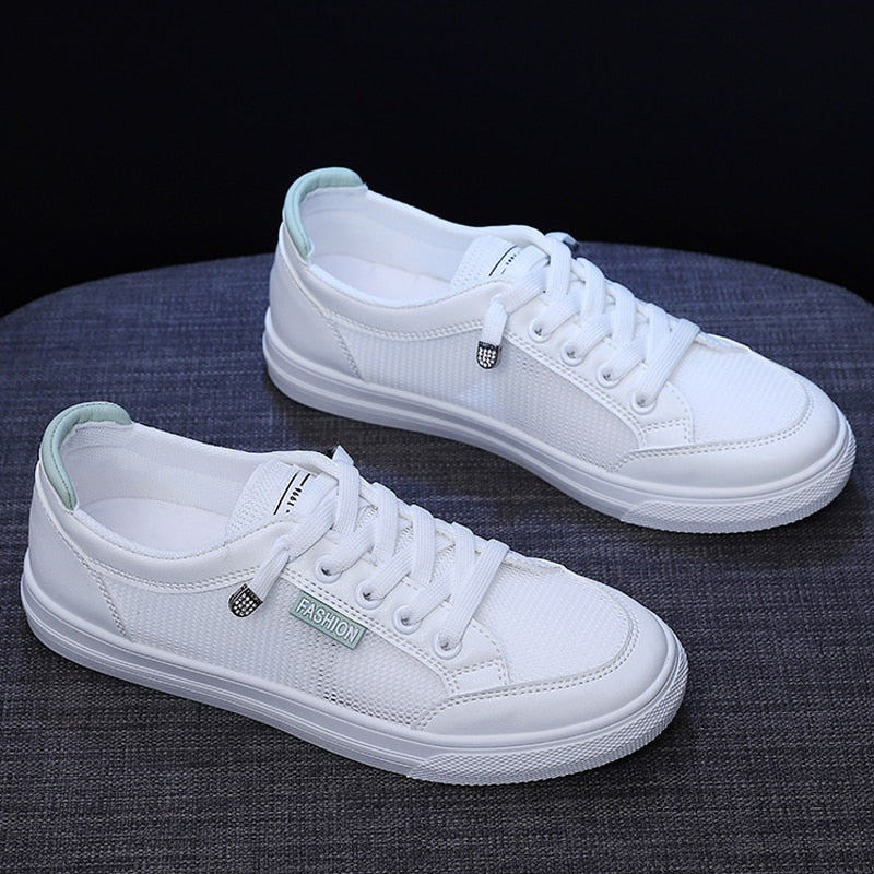 Weiße Sneaker aus Canvas mit Schnürsenkeln, modisch, unisex, auf grauem Hintergrund.