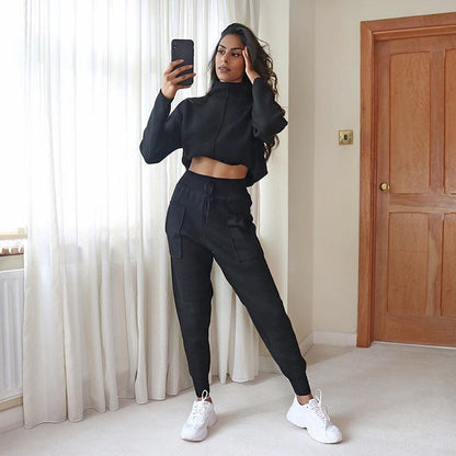 Frau in schwarzem Jogginganzug, Selfie, weiße Sneaker, modernes Wohnzimmer, Freizeitmode.