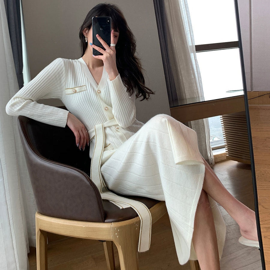 Frau in weißem Strickkleid, sitzt auf Stuhl, modernes Interieur, Selfie im Spiegel.