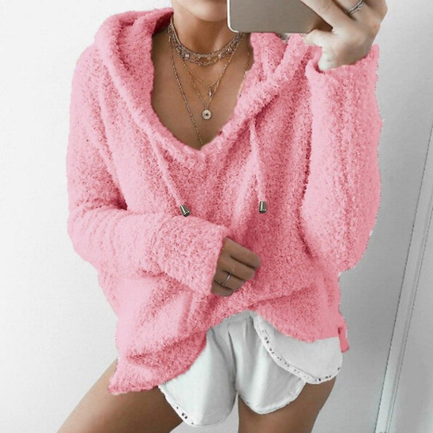 Frau in rosa Fleece-Hoodie und weißen Shorts, gemütliche Damenmode, lässiger Stil.
