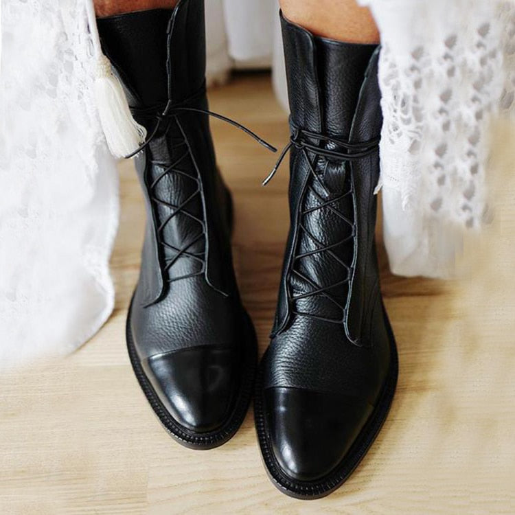 Schwarze Lederstiefel mit Schnürung, Damenmode, elegantes Design, auf Holzboden.