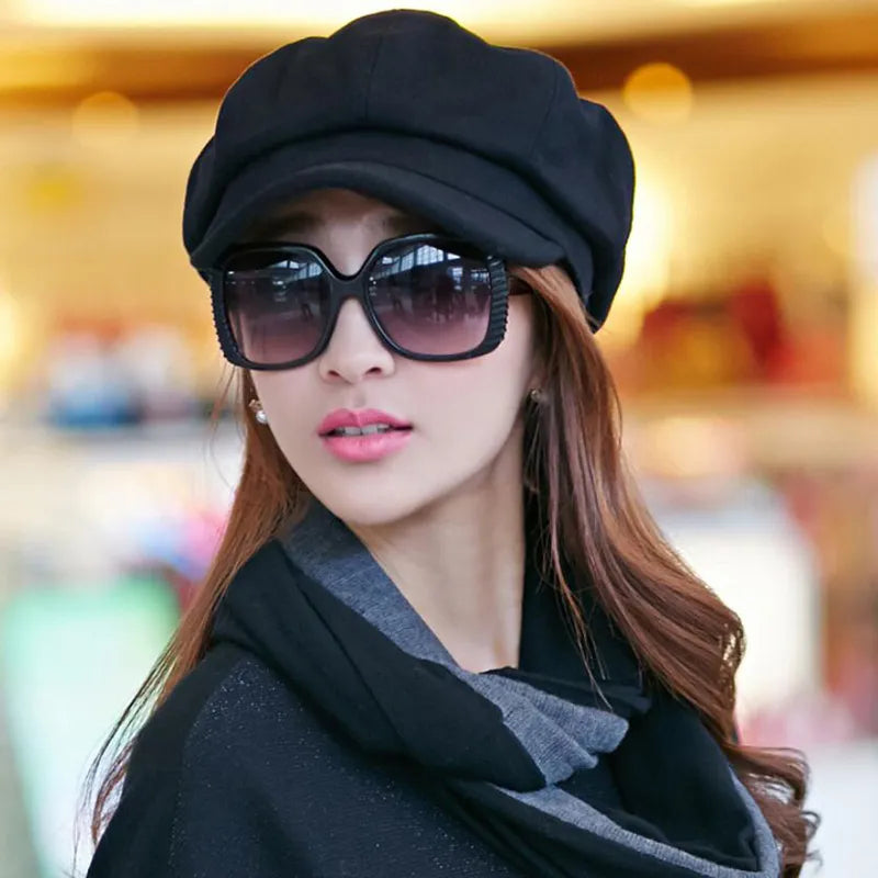 Frau mit schwarzer Schiebermütze und Sonnenbrille, modisches Accessoire, stilvoller Look.