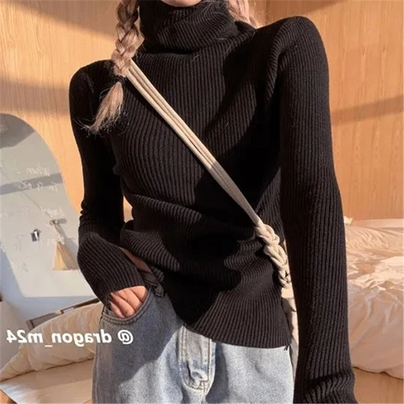 Frau in schwarzem Rollkragenpullover, Zopf, Jeans, beige Tasche, lässiger Herbstlook.