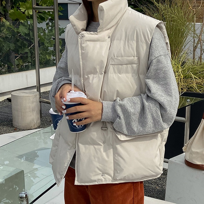 Frau in weißer Daunenweste, grauem Pullover, hält Kaffee, Herbstmode, Outdoor-Café.