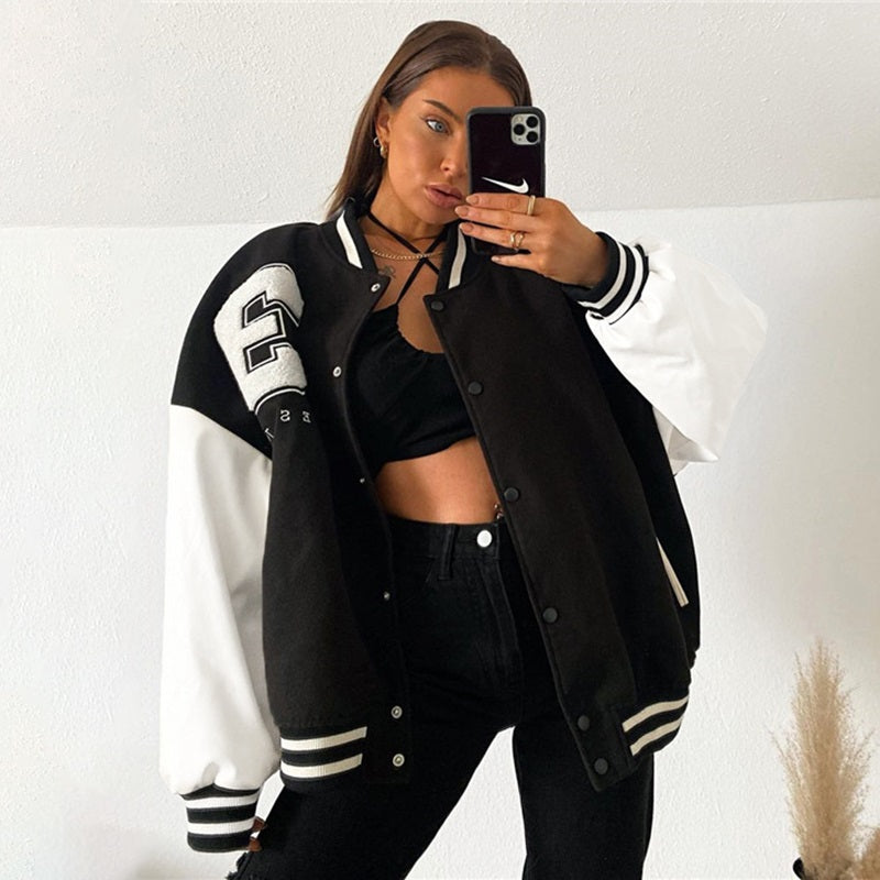 Frau in schwarzer Collegejacke mit weißen Ärmeln, Nummer 23, modisch, lässig, Selfie.