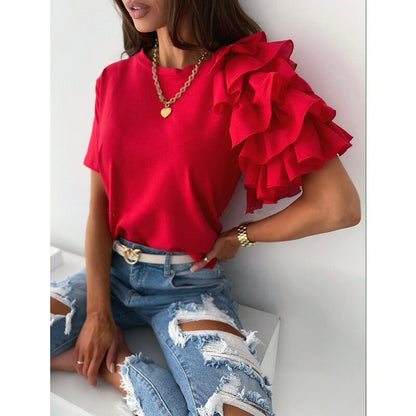 Frau in rotem Rüschen-Top, zerrissene Jeans, goldene Halskette, modisches Outfit.