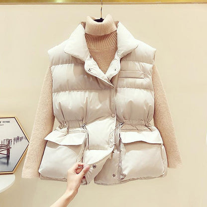 Weiße Daunenweste Damen, ärmellos, mit Taschen, über beigem Rollkragenpullover.