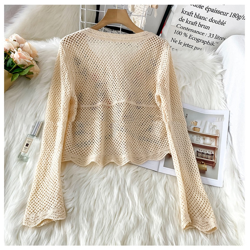 Beige Strickjacke Damen, Netzdesign, Langarm, modisch, auf weißem Fellhintergrund.