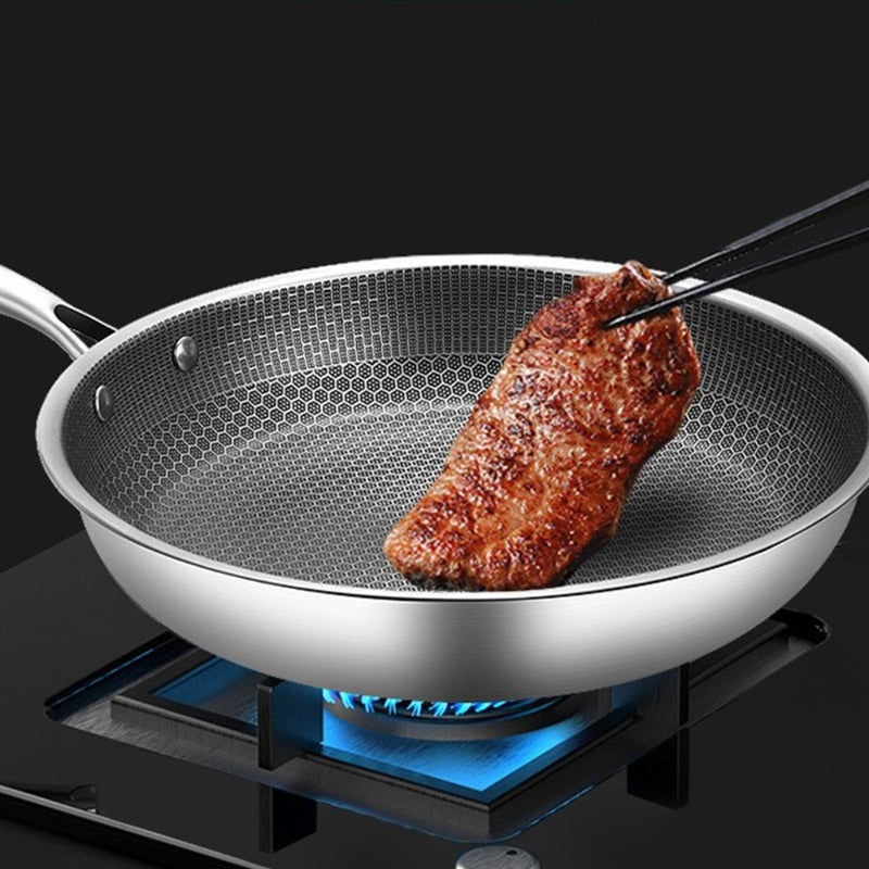 Edelstahlpfanne mit Steak, Antihaftbeschichtung, auf Gasherd, Kochgeschirr, Küche.