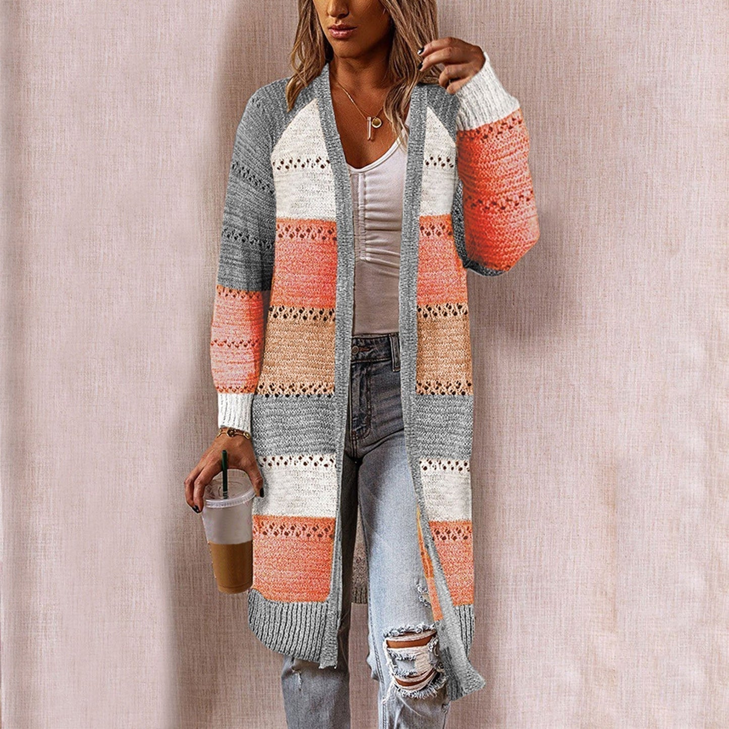 Frau trägt gestreiften Strick-Cardigan in Grau, Orange und Weiß, lässiger Herbst-Look.