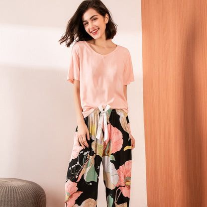 Frau in rosa T-Shirt und bunter Blumenhose, lächelnd, modisch, lässige Damenbekleidung.