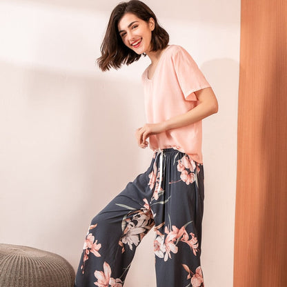 Frau in rosa T-Shirt und blumiger Hose, lächelnd, moderne Freizeitmode, Innenraum.