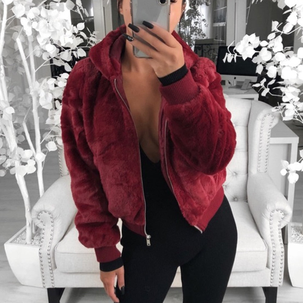 Frau in roter Kunstpelzjacke, Reißverschluss, Kapuze, modisch, gemütlich, Innenraum.