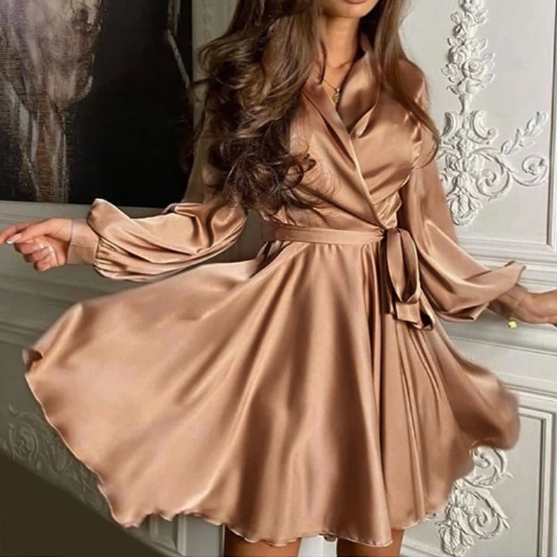 Frau in elegantem, seidigem, bronzefarbenem Wickelkleid mit langen Ärmeln, modisch, stilvoll.