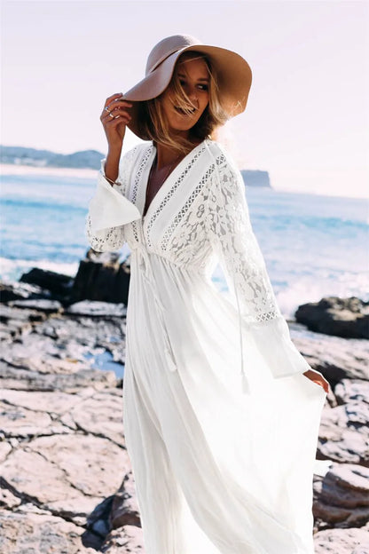 Frau in weißem Spitzenkleid und Hut am Strand, Sommermode, Boho-Stil, Meereshintergrund.