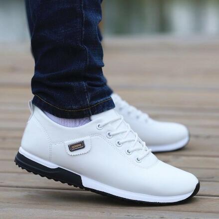 Weiße Herren-Sneaker aus Leder, sportlich, bequem, mit Schnürsenkeln, auf Holzdeck.