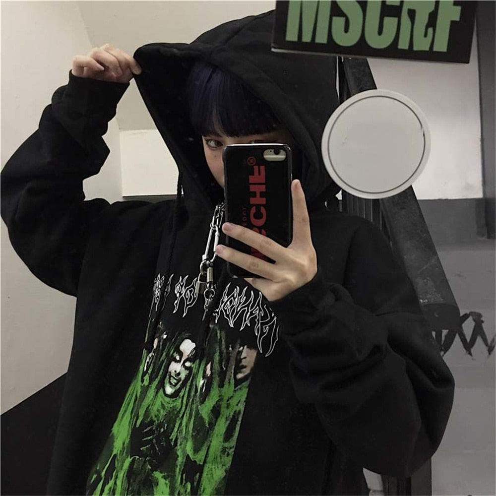 Person in schwarzem Hoodie mit grünem Print, Selfie im Spiegel, Streetwear, urbaner Stil.