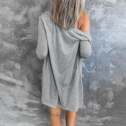 Frau in grauem, schulterfreiem Kleid vor grauer Wand, lässige Mode, Rückansicht.