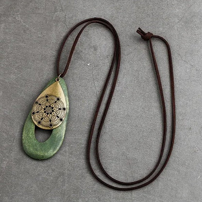 Grüner Holzanhänger mit goldener Spitze, braunes Lederband, handgefertigter Schmuck, Boho-Stil.