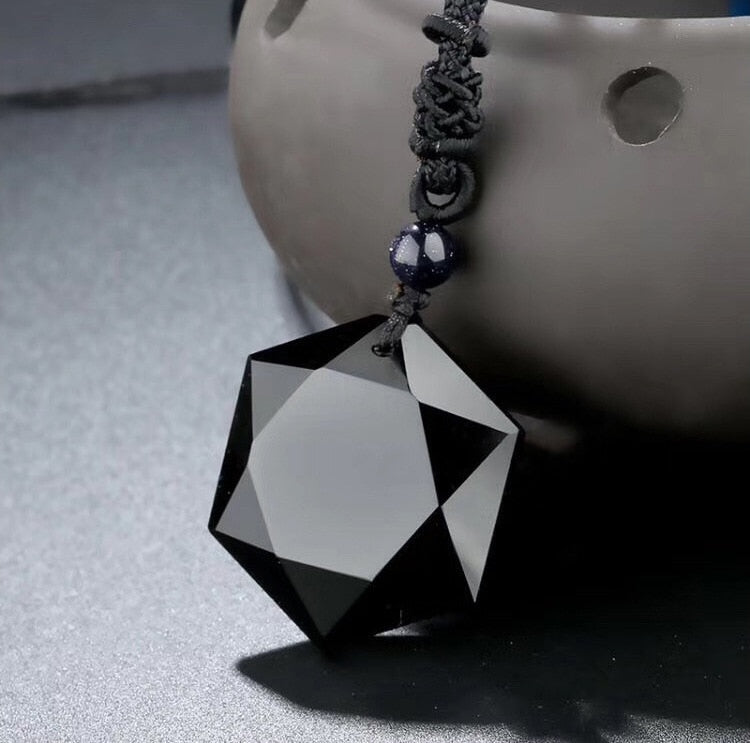 Schwarzer Kristallanhänger, facettiert, geometrisch, an schwarzer Kordel, eleganter Schmuck.