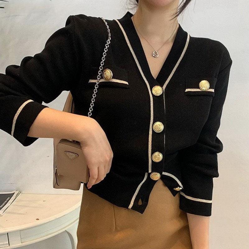 Frau trägt schwarze Strickjacke mit goldenen Knöpfen, elegantes Design, modische Damenmode.