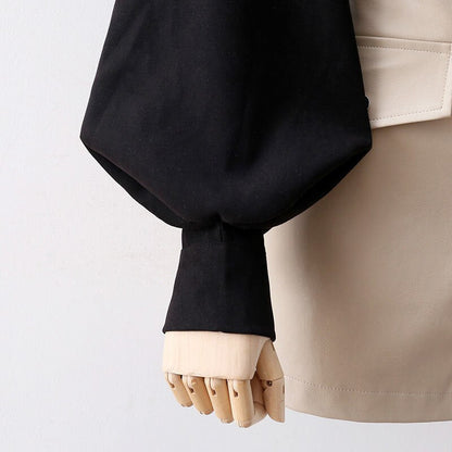 Schwarze Bluse mit Puffärmeln, Holzhand, beiger Rock, elegante Damenmode.