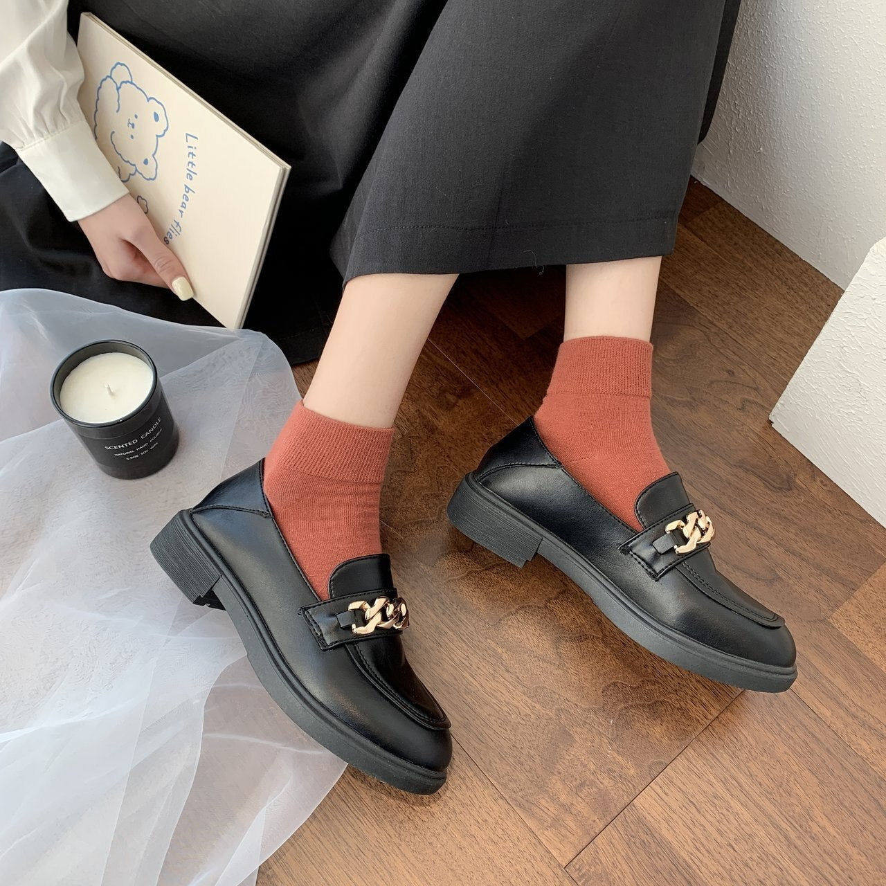 Schwarze Loafer mit goldener Kette, Damenmode, elegante Schuhe, Herbststil, Holzboden.
