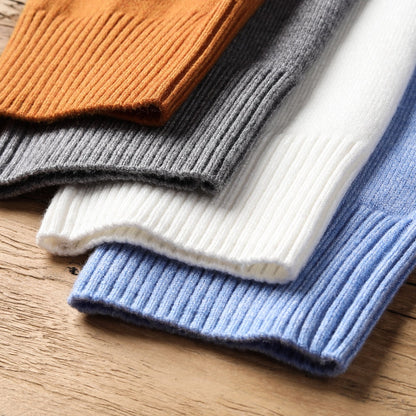 Vier gestrickte Pullover in Orange, Grau, Weiß und Blau auf Holztisch, Baumwolle, Herbstmode.