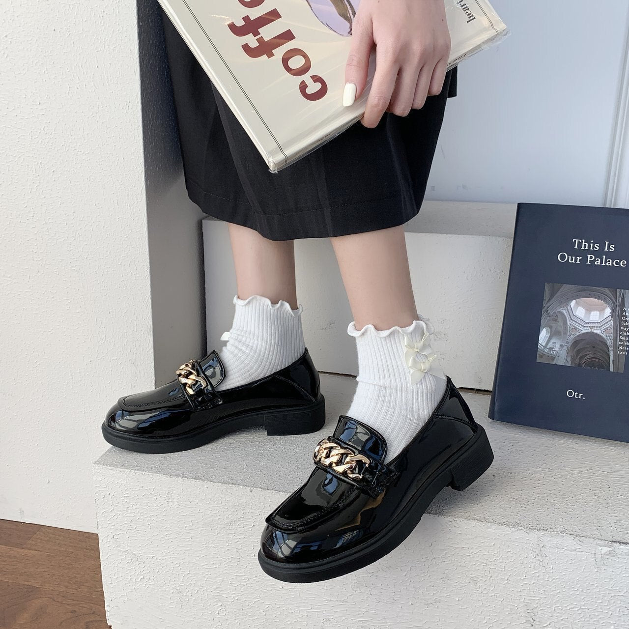 Schwarze Lackleder-Loafer mit goldener Kette, Damenmode, eleganter Schuh, stilvoller Look.
