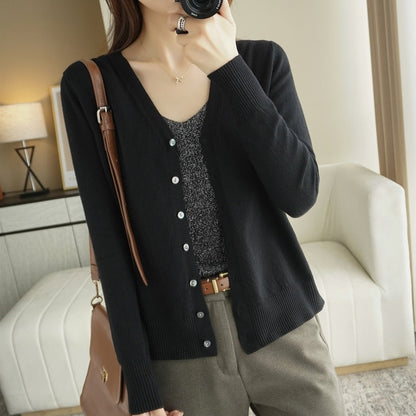 Frau in schwarzem Cardigan und grauem Top, braune Hose, modisch, lässig, Innenraum.