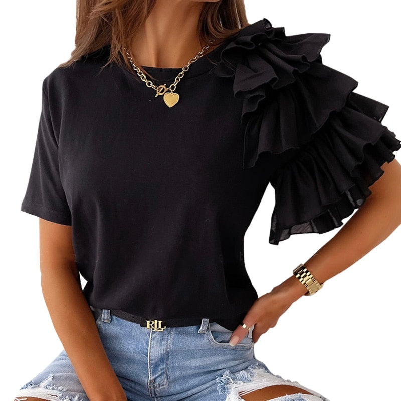 Frau in schwarzem Rüschen-Top, Herzanhänger-Kette, zerrissene Jeans, modisch, elegant.
