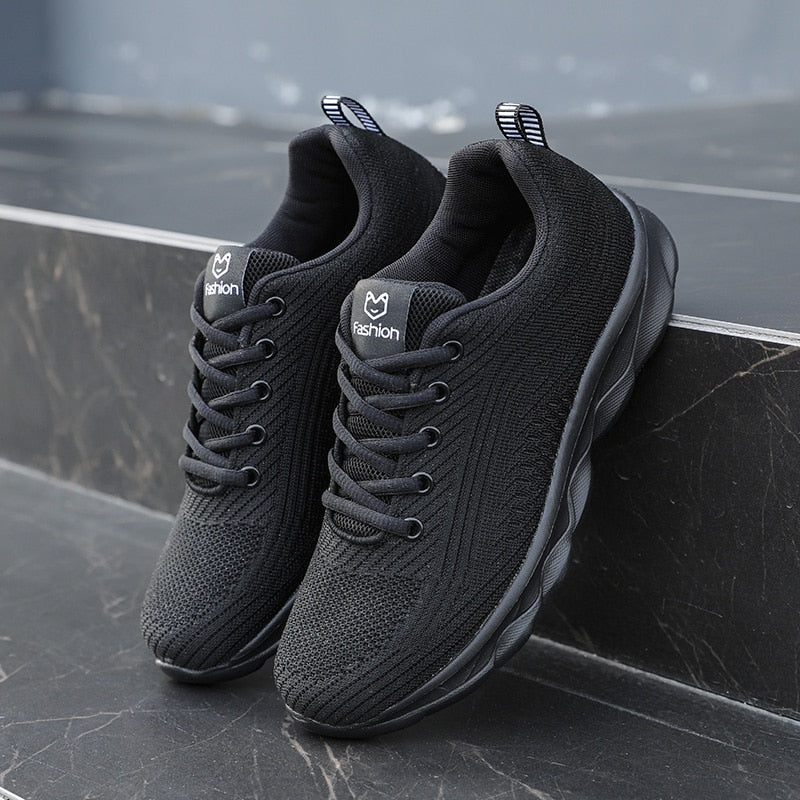 Schwarze Sportschuhe, atmungsaktiv, rutschfest, für Herren, auf Marmortreppe.