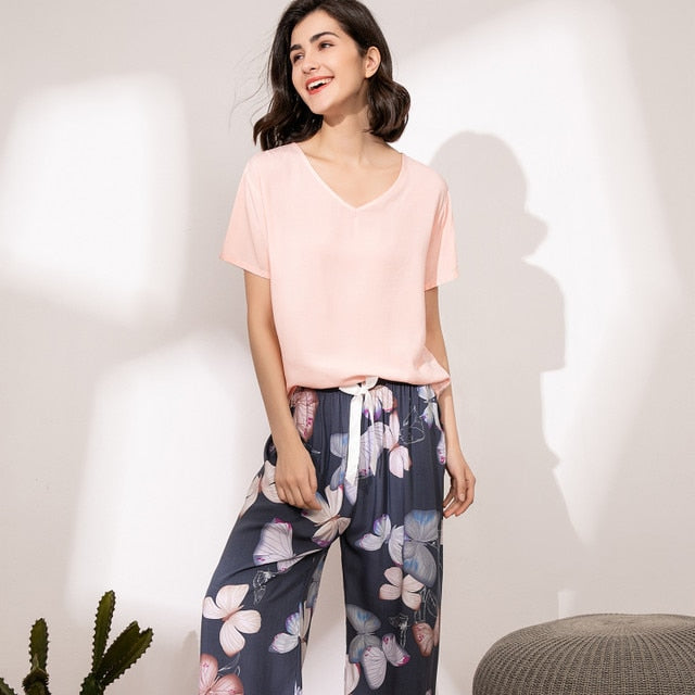 Frau in rosa T-Shirt und blumiger Hose, lächelnd, modisch, lässig, Sommerkleidung.