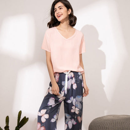 Frau in rosa T-Shirt und blumiger Hose, lächelnd, modisch, lässig, Sommerkleidung.