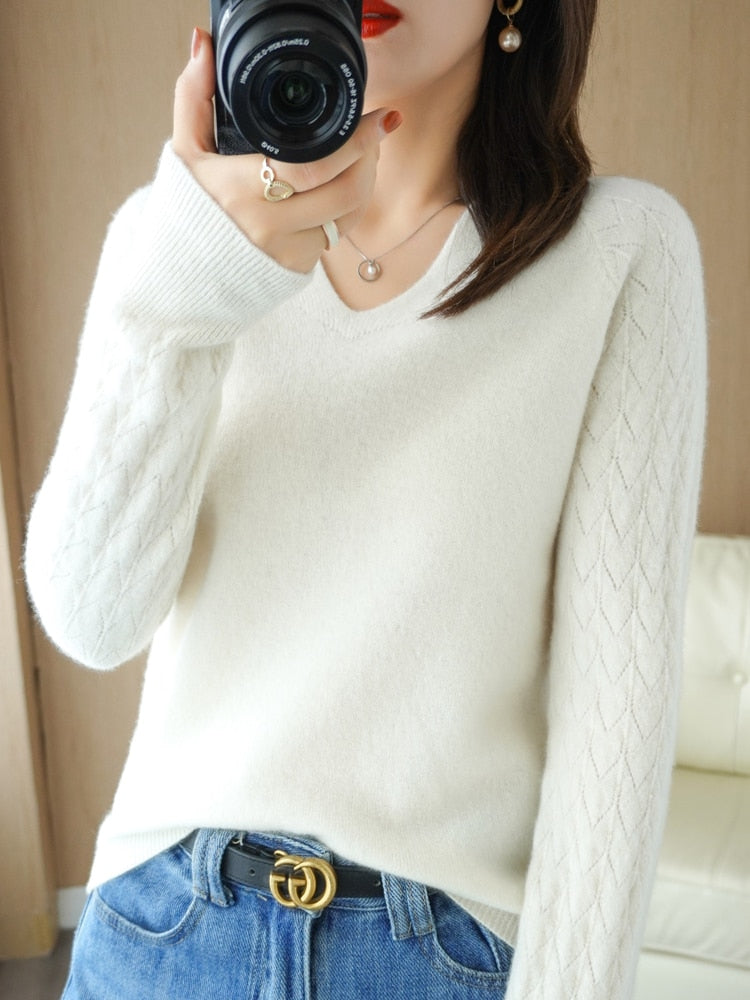 Frau in weißem Strickpullover mit Kamera, Jeans und Schmuck, modisch, stilvoll, Innenraum.