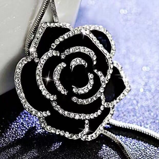 Schwarze Rosenbrosche mit Kristallen, eleganter Schmuck, glänzend, modisches Accessoire.