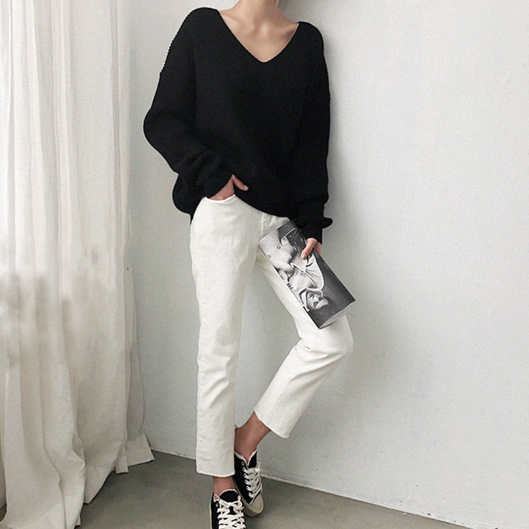 Frau in schwarzem Pullover und weißer Hose, lässiger Look, Modefotografie, minimalistisch.