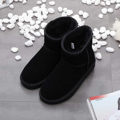 Schwarze Winterstiefel aus Wildleder, warm gefüttert, auf grauem Boden mit weißen Steinen.