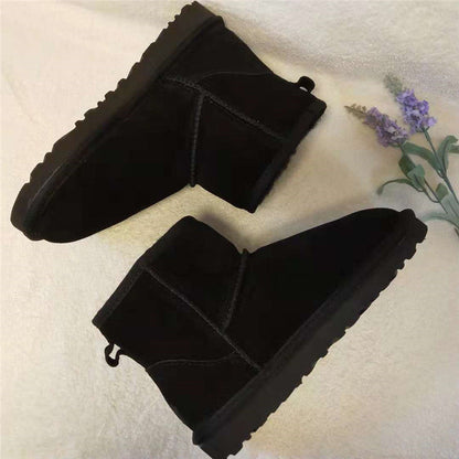Schwarze Winterstiefel aus Wildleder mit flacher Sohle, warm gefüttert, auf beigem Hintergrund.