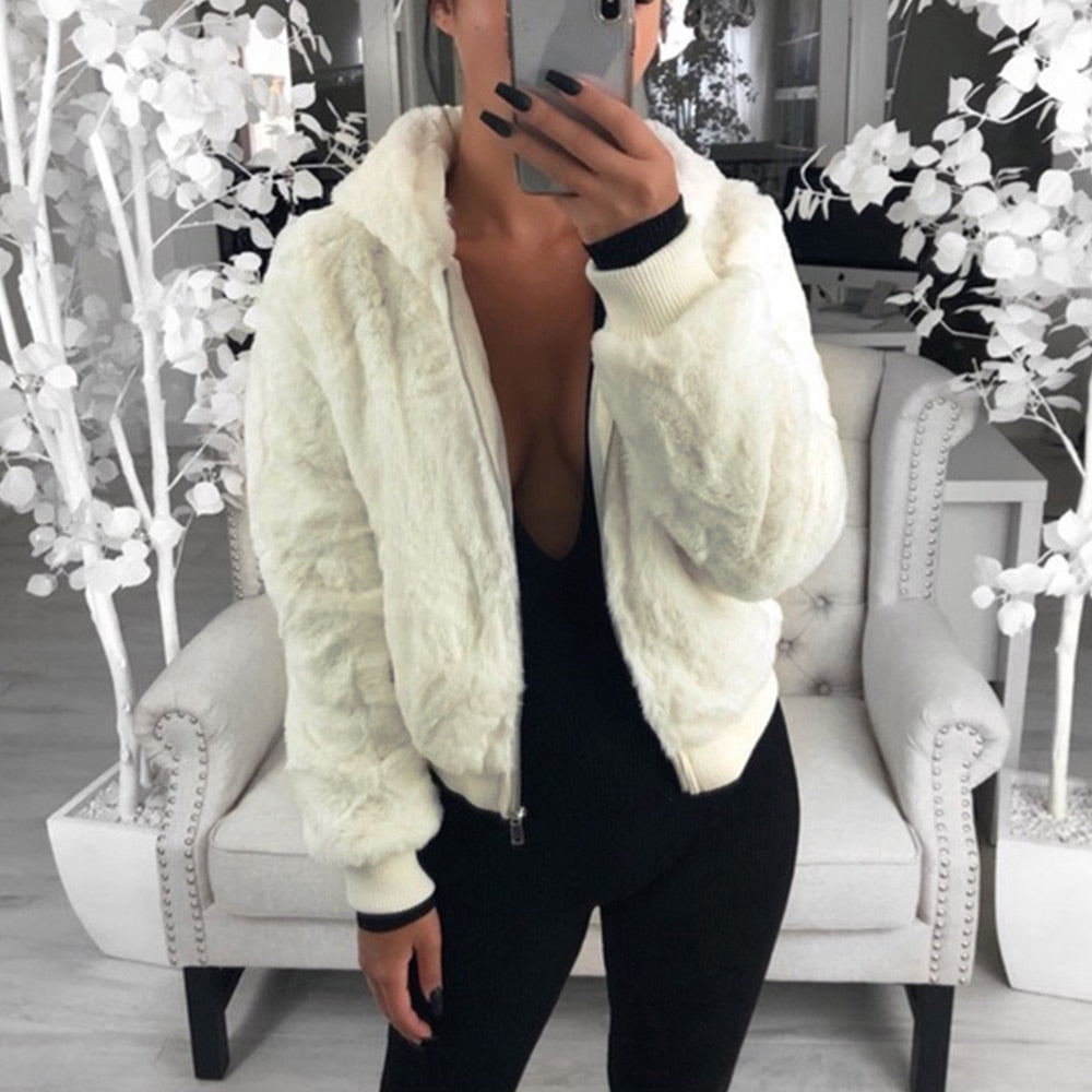 Frau in weißer Kunstpelzjacke, schwarzer Overall, modernes Wohnzimmer, stilvolle Mode.