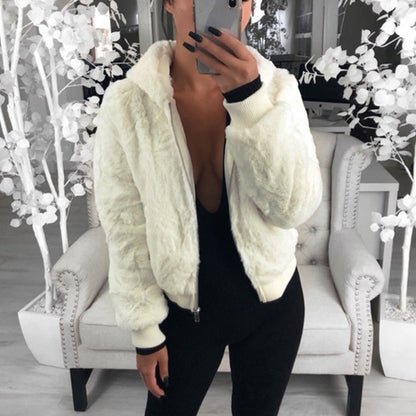 Frau in weißer Kunstpelzjacke, schwarzer Overall, modernes Wohnzimmer, stilvolle Mode.