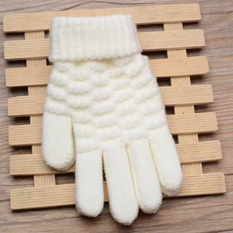 Weiße gestrickte Winterhandschuhe aus Wolle, warm und weich, auf Holzuntergrund.