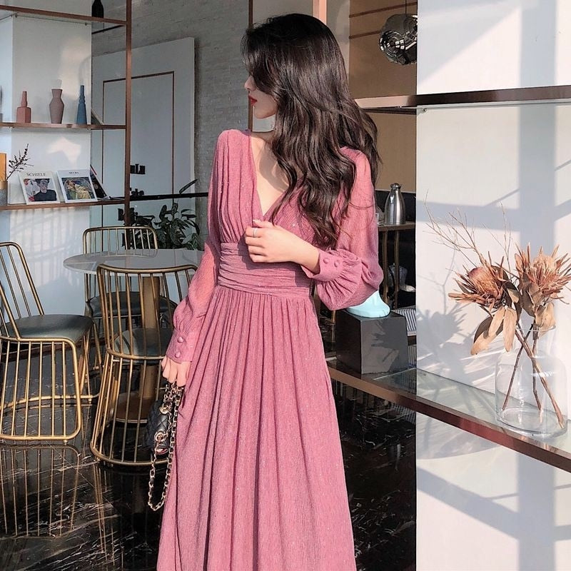 Frau in rosa Maxikleid mit langen Ärmeln in modernem Wohnzimmer, elegantes Design.