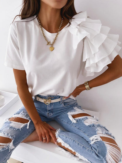 Frau in weißem Rüschen-T-Shirt und zerrissener Jeans, modisches Outfit, Goldkette.