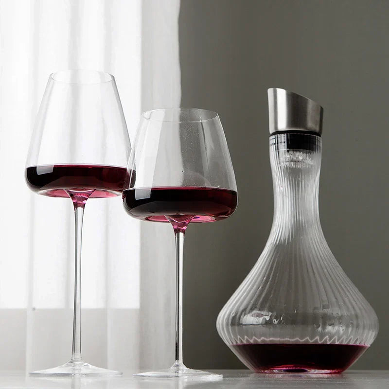 Två glas med rödvin bredvid en räfflad karaff med metallpropp vid ett fönster 3
